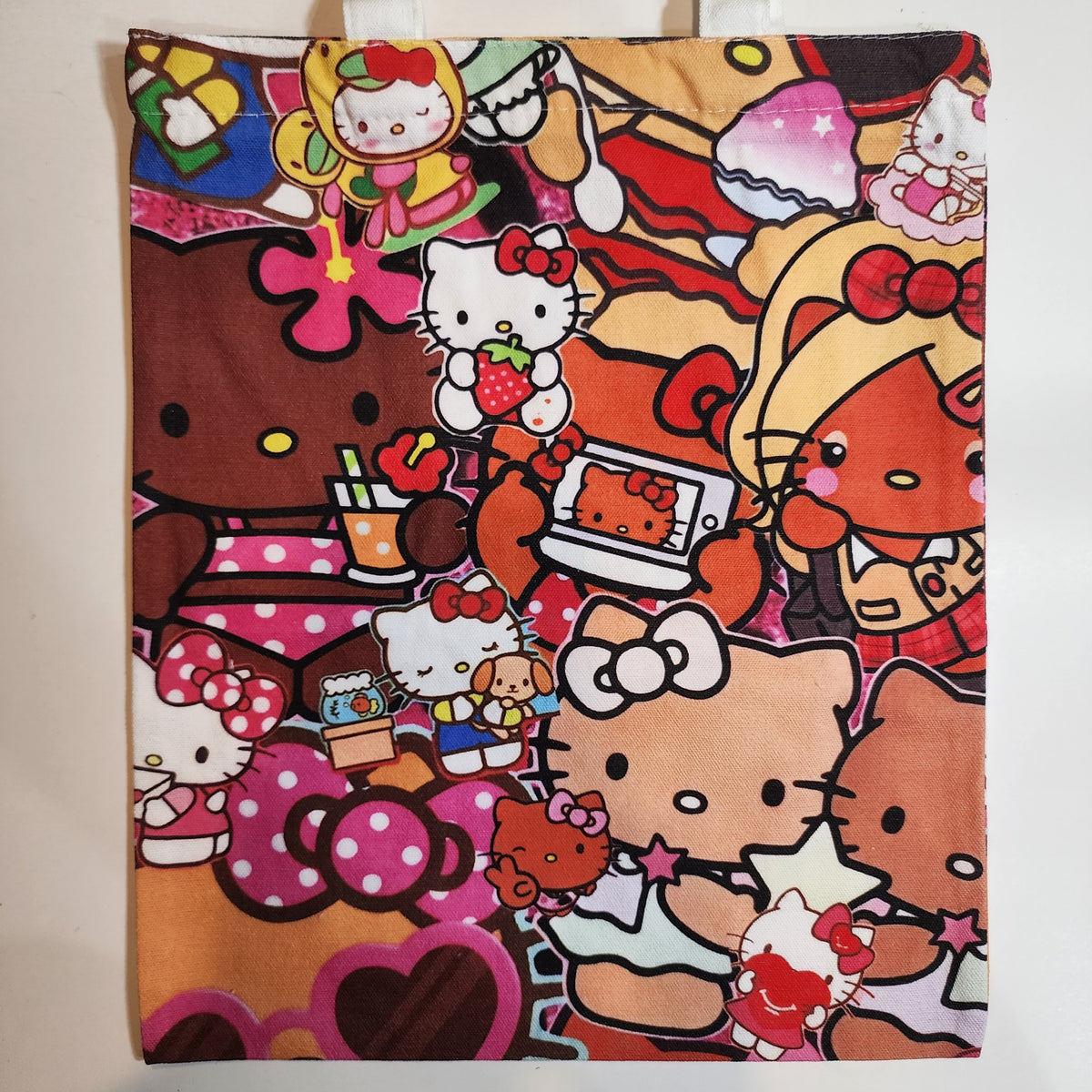A fabric tote bag featuring a dense, colorful collage print of Hello Kitty characters in various poses and outfits, set against a plain light background.